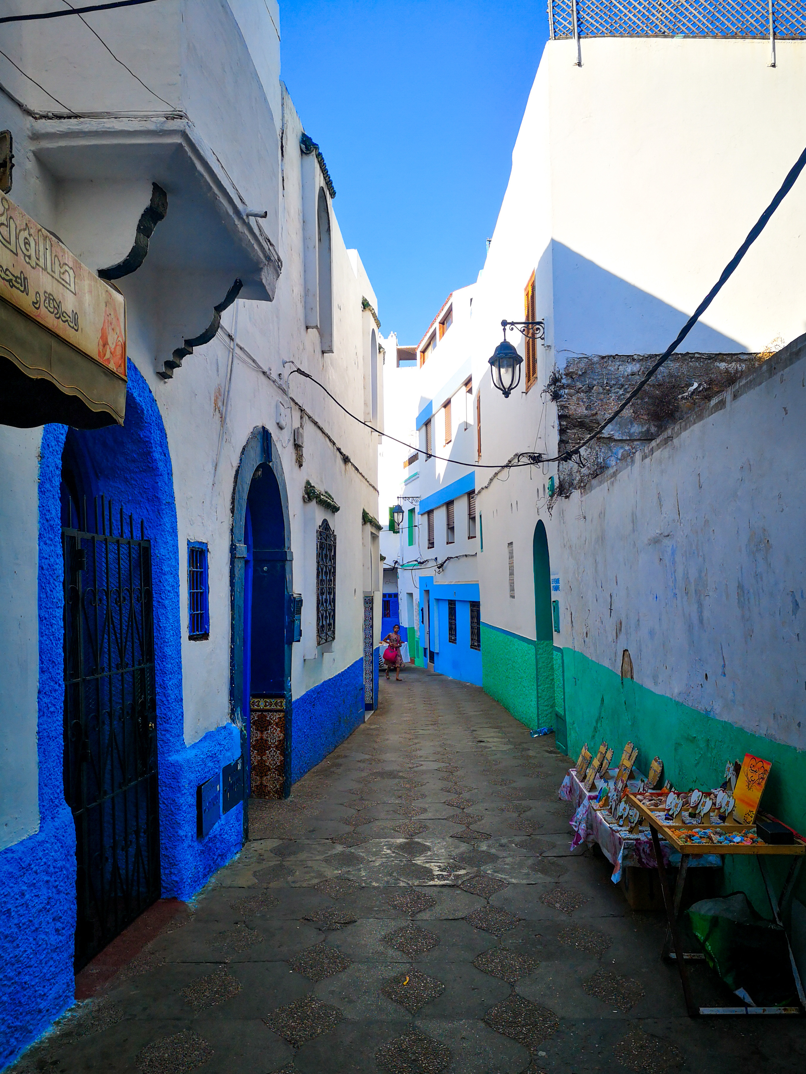 Ruelle bleue et blanche d'Asilah avec des étals de vendeurs