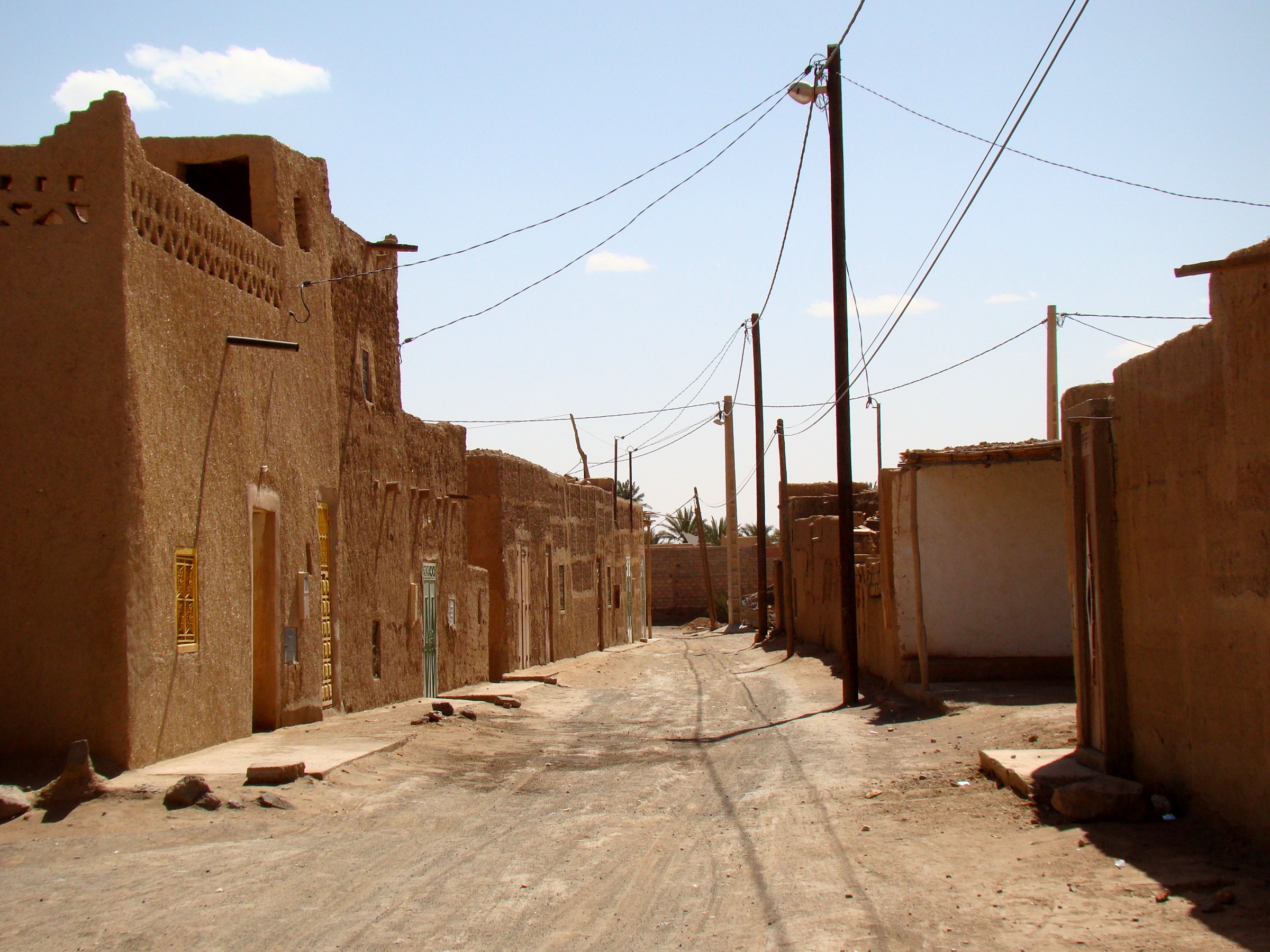Rue bordée de maisons en terre dans la partie ancienne de Merzouga