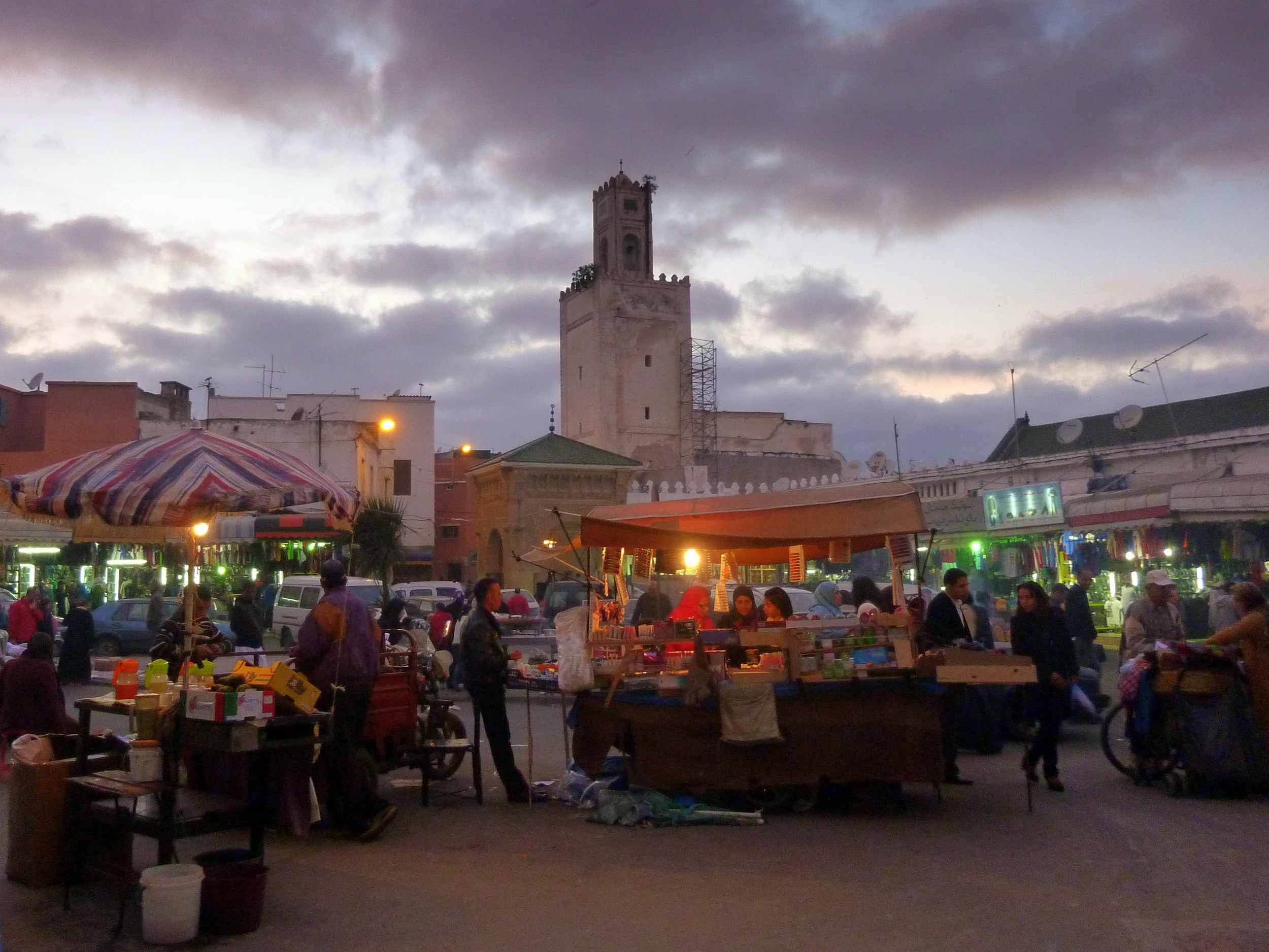 Étals d'un marché éclairés au crépuscule à El Jadida (Mazagan), avec une tour en arrière-plan