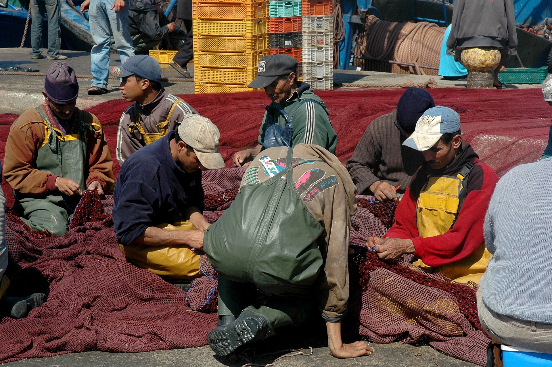 Pêcheurs assis sur le quai réparant leurs filets au port d'Essaouira.
