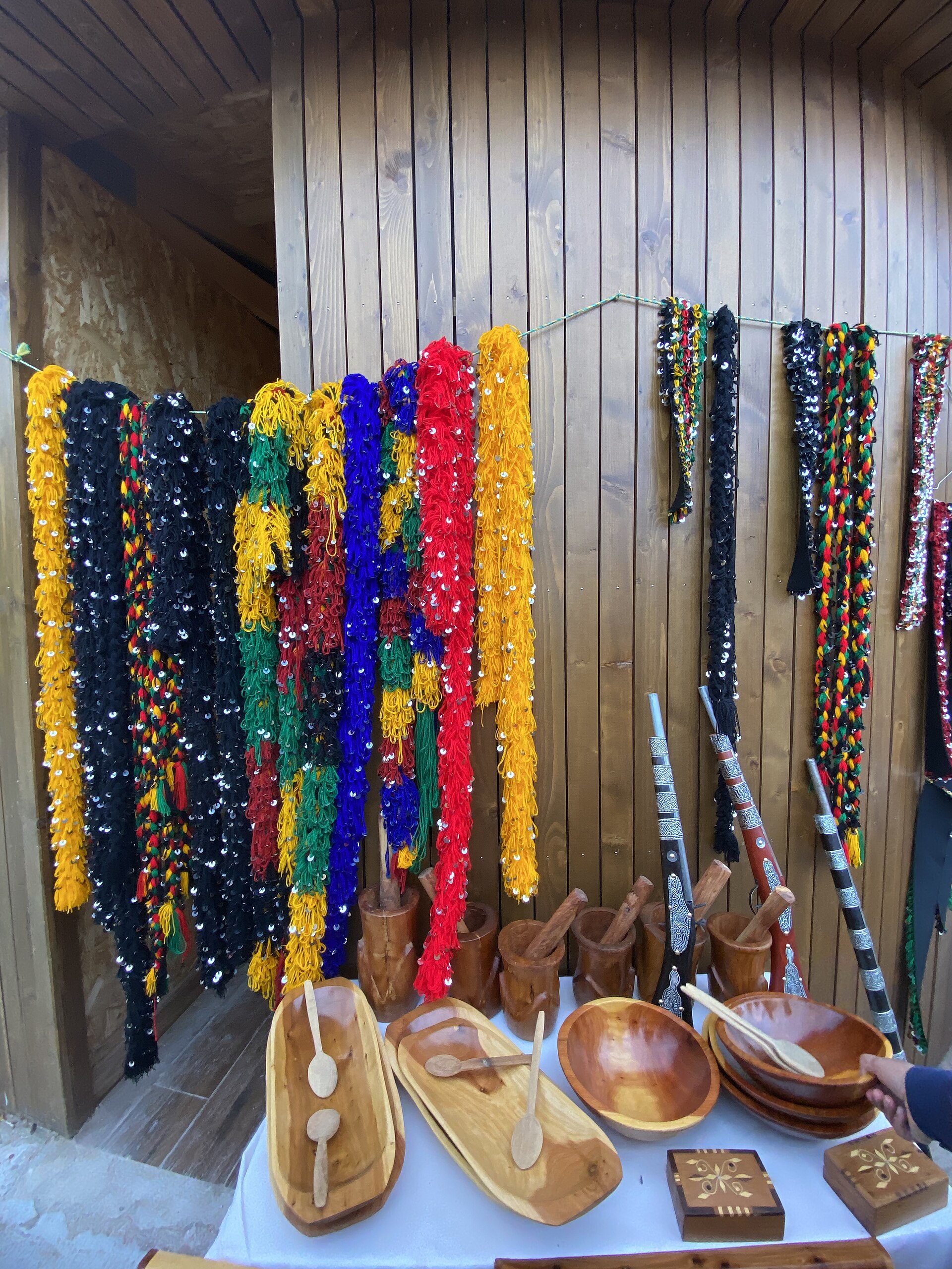 Objets d'artisanat en bois et parures colorées exposés sur un étal à Ifrane