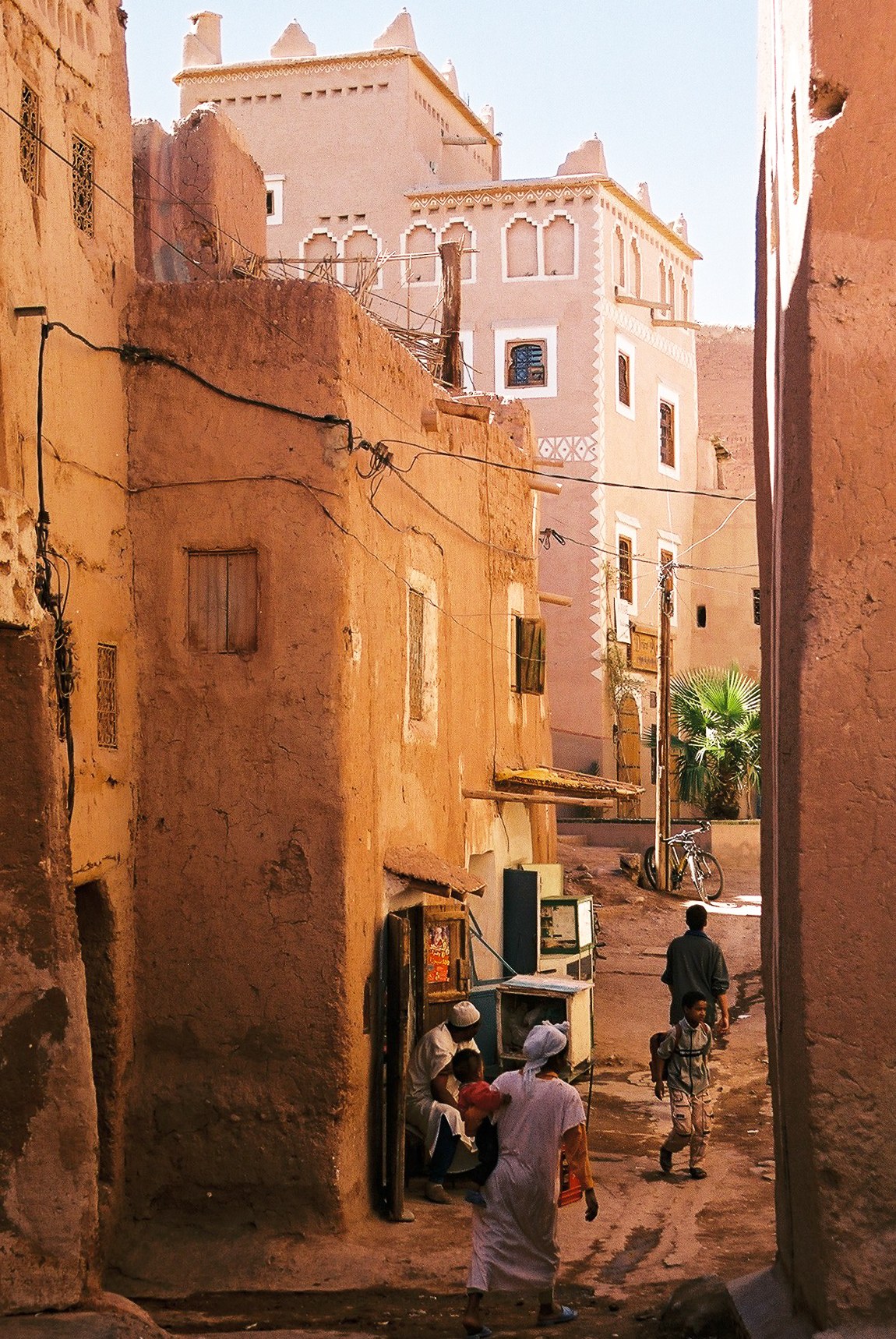 Ruelle en terre ocre du quartier de la Kasbah Taourirt à Ouarzazate avec des passants