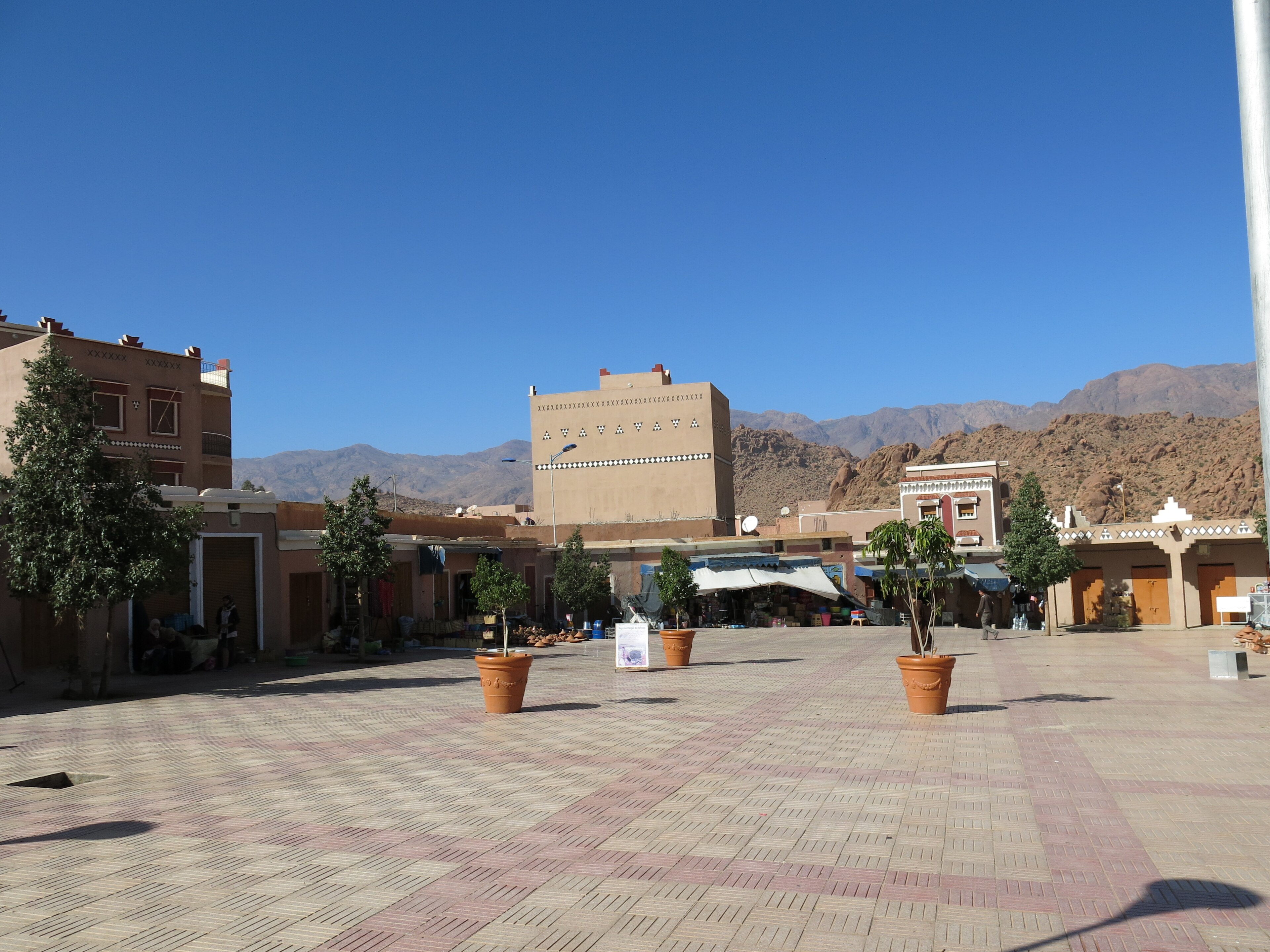 Place pavée de Tafraout entourée de bâtiments ocre, avec les montagnes en arrière-plan