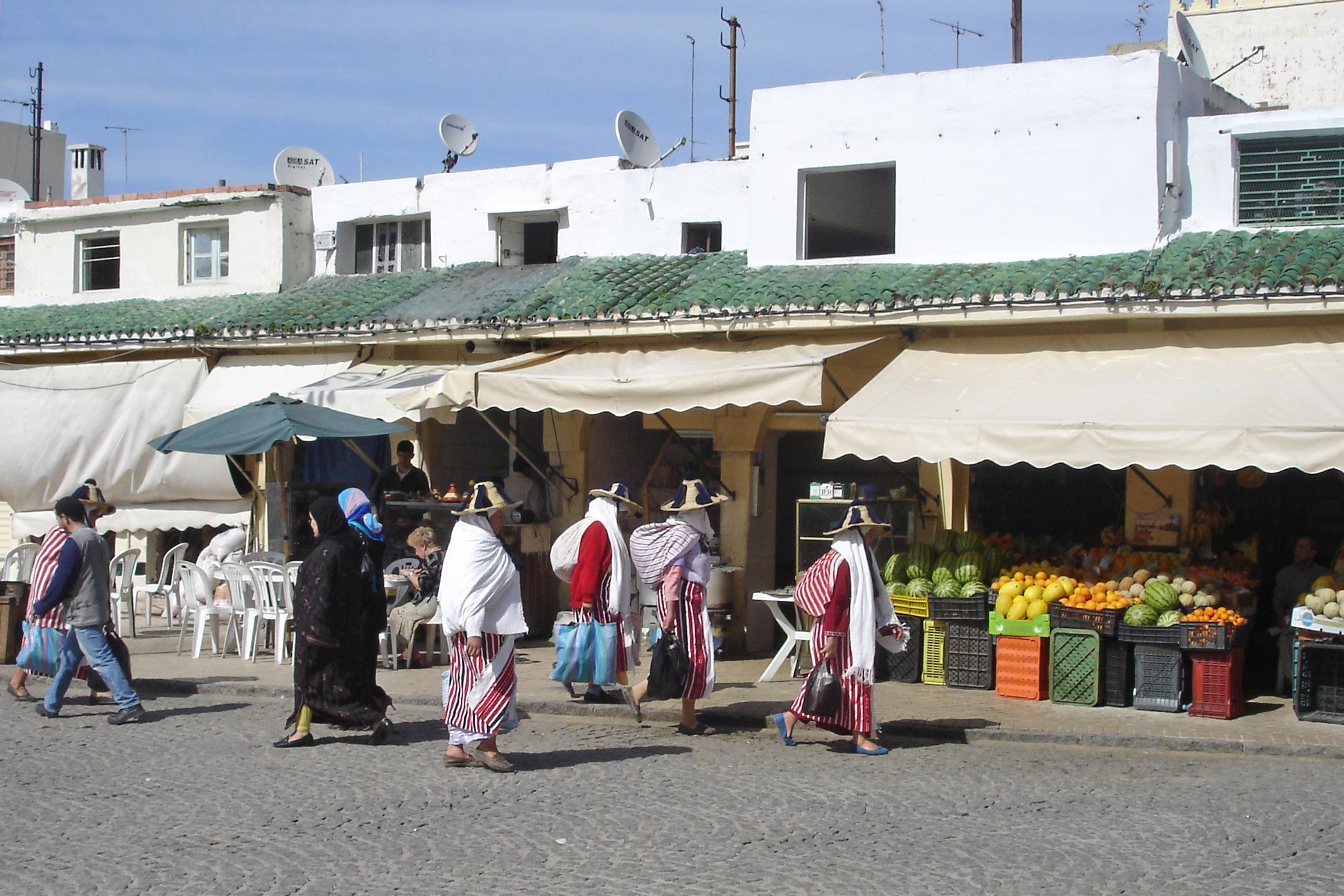 Femmes en costume traditionnel devant les étals de fruits du marché du Grand Socco à Tanger