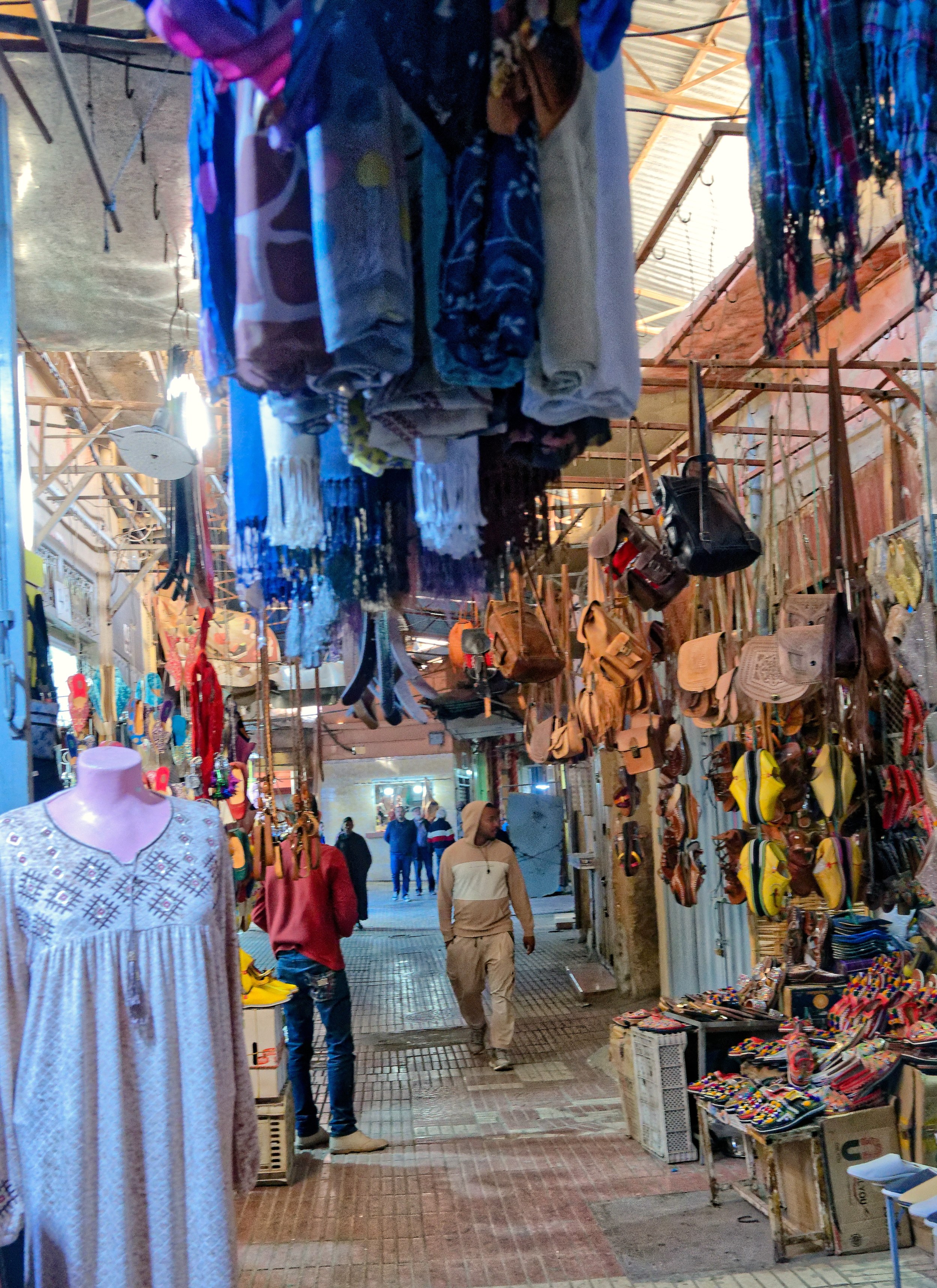 Allée commerçante de Taroudant avec vêtements et sacs suspendus