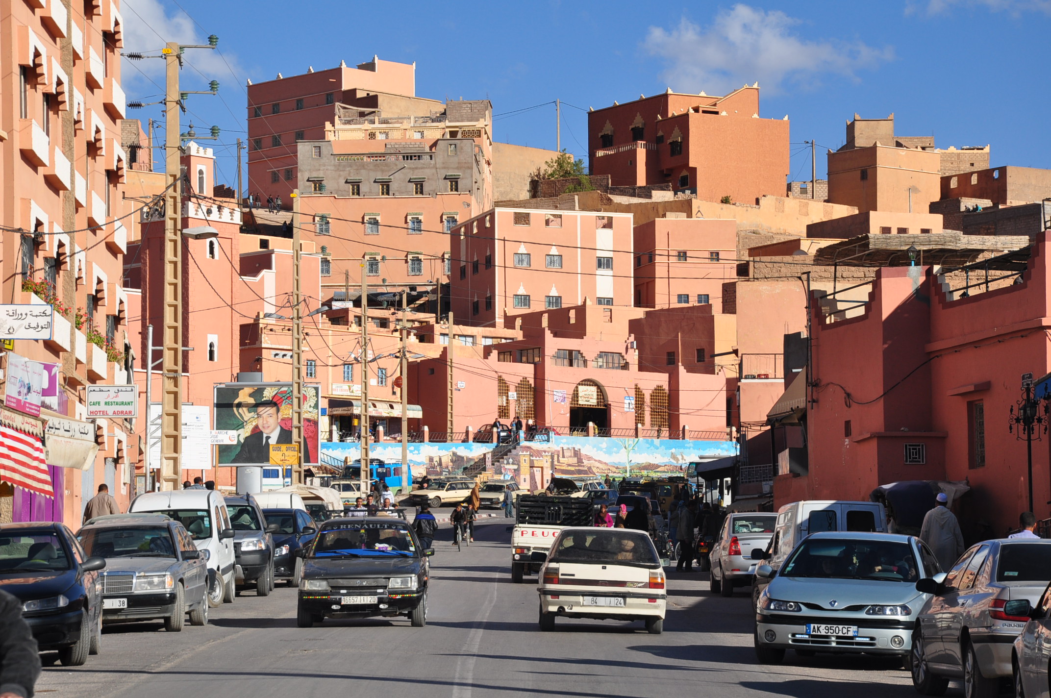 Rue principale animée de Boumalne Dadès avec voitures et immeubles ocre